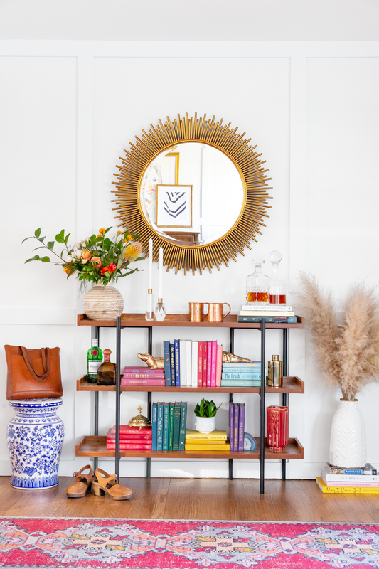 Bookshelf with gold mirror and colorful books