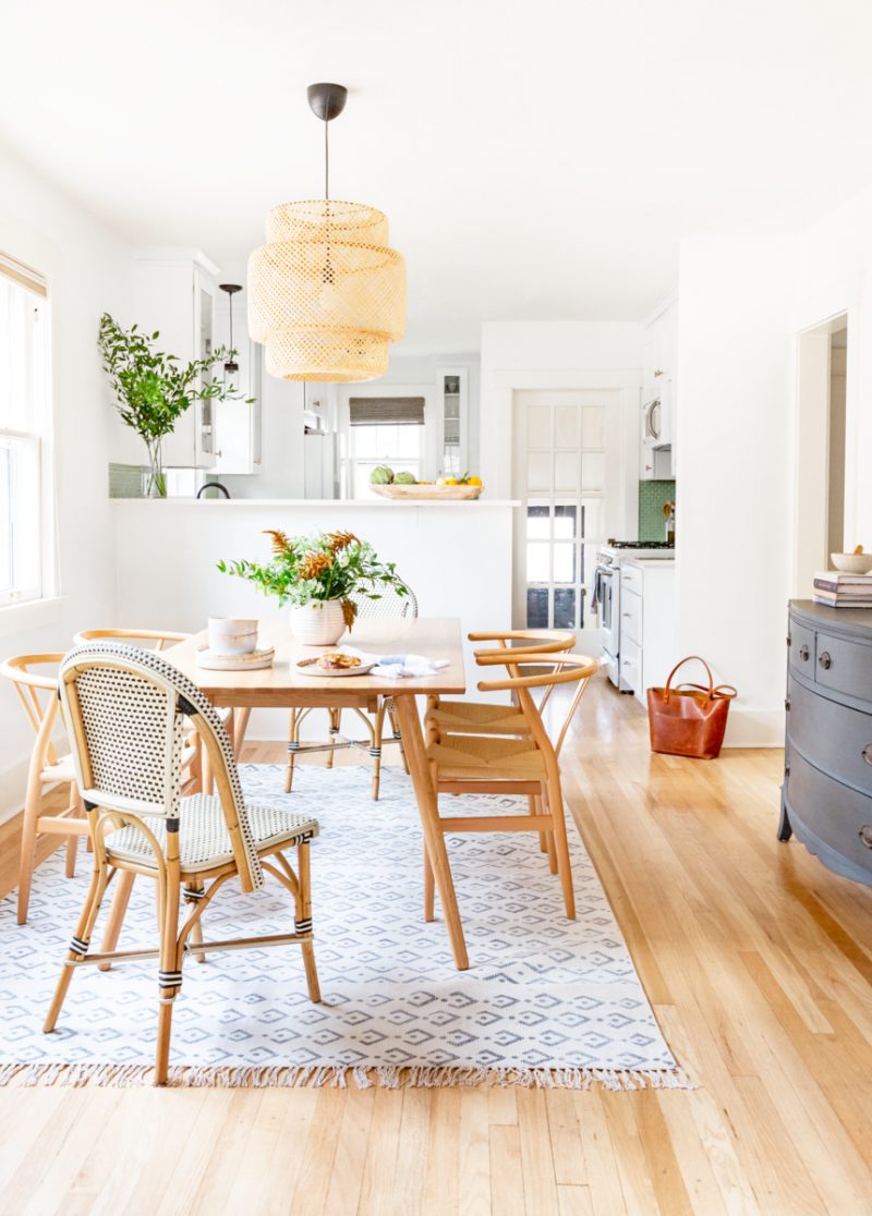 This Cali-Cool dining room features a clean, modern dining table, wishbone chairs, a rattan pendant, and a bit of bohemian flair